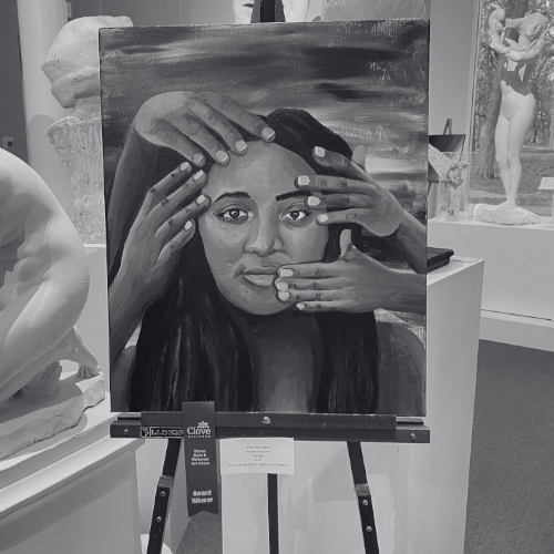 A black and white photo of a painting on an easel. The painting depicts a person's face with multiple hands touching it.