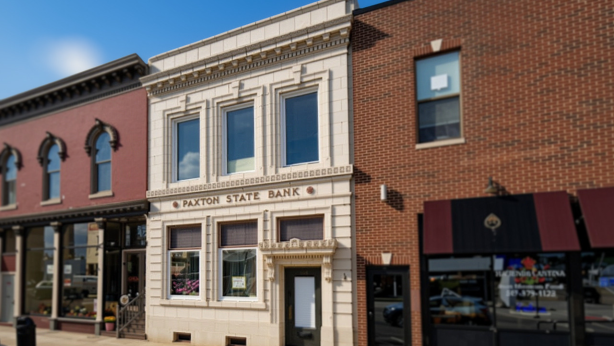 Clove Alliance's Paxton office, a two-story building labeled “Paxton State Bank,” sits between other commercial storefronts on a sunny day.