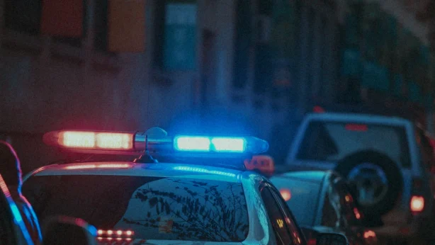 a close cropped photo of a police car with its lights on parked on a street at night